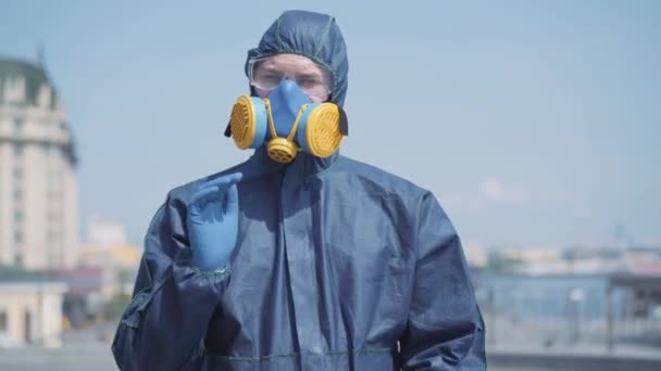 Retrato de homem confiante em terno químico esticando a mão em luva azul protetora para câmera. Trabalhador caucasiano de fato químico a parar o coronavírus. Pandemia de Covid-19, poluição atmosférica radioactiva . — Vídeo de Stock