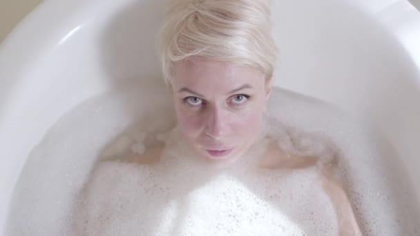Молода жінка занурюється у ванну. Вид зверху портрет блондинки радісної чуттєвої леді розважається у ванній кімнаті. Радість, спосіб життя, краса, особиста гігієна . — стокове відео
