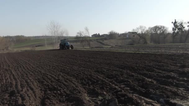 Gros plan de tracteur agricole sillonnant un champ fertile le jour ensoleillé du printemps. Machines fonctionnant sous le ciel bleu du printemps. Concept d'agriculture, agronomie, agriculture, jardinage . — Video