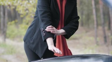 Yetişkin sarışın beyaz kadın kollarını sıvayıp arabanın kaputunu inceliyor. Kendine güvenen kadın sürücünün portresi banliyö yolunda otomobil arızasını tamir ediyor. Yaşam tarzı, özgüven, kaza.