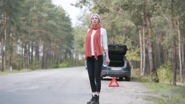 Femme blonde désespérée faisant du stop sur la route de banlieue. Portrait large de la conductrice caucasienne stressée ayant la casse de voiture sur l'autoroute de campagne. Problème, accident, mode de vie, voyage . — Video