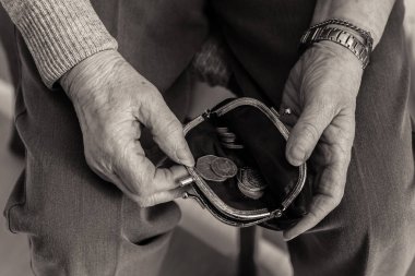 Elderly lady's hands checking money in her purse. clipart