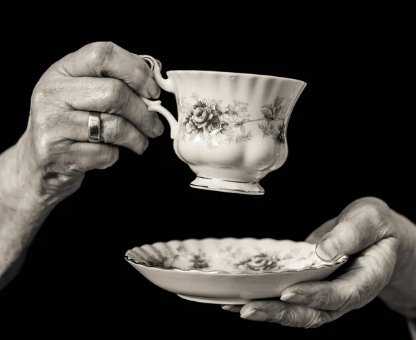 Yaşlı kadının ellerinde düzenlenen geleneksel çay fincanı ve tabağı.