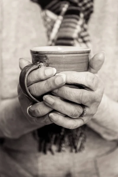 Tek renkli yakın çekim emekliler elinde sıcak bir içecek çukurluğu. — Stok fotoğraf