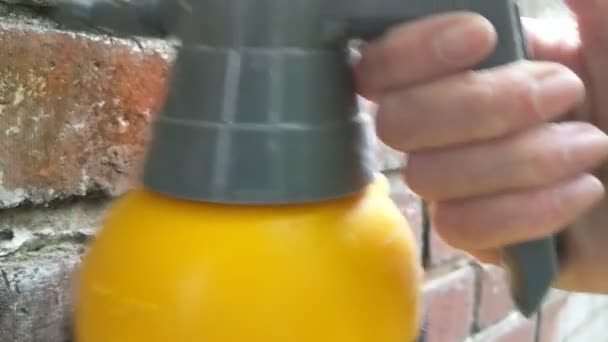 Mujer rociando la pared de ladrillo con agua antes de señalar. Primer plano. . — Vídeos de Stock