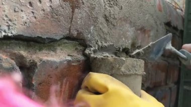 Kadın harç ile tuğla duvar işaret. Eller kapanır.