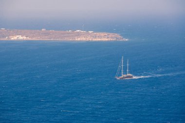 Santorini 'deki Oia köyünden deniz manzaralı ve güneşli bir havada üzerinde gemi var.