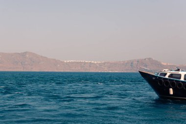 Santorini 'deki Oia köyünden deniz manzaralı ve güneşli bir havada üzerinde gemi var.