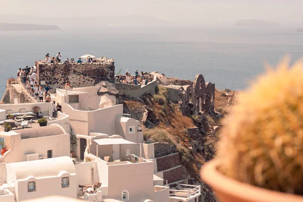 Oia, Santorini - 07 de julio de 2019: vista de la fortaleza de Oia con los visitantes caminando con el tiempo soleado — Foto de Stock