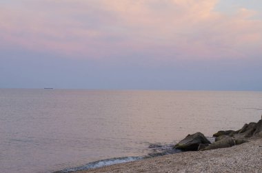 Taşlık bir kıyı ile denizde akşam günbatımı