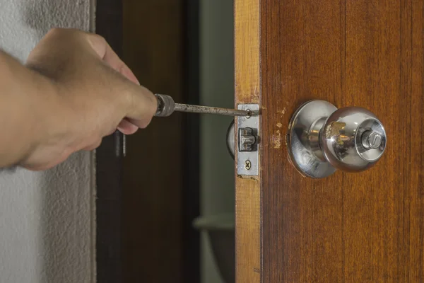 Cerrajero fijar una vieja perilla en la puerta de madera en casa — Foto de Stock