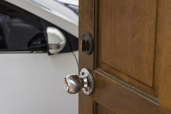 Bouton en argent sur porte en bois maison ouverte sur une voiture blanche — Photo