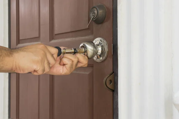 Cerrajero utilizar su herramienta abrir la puerta de madera —  Fotos de Stock