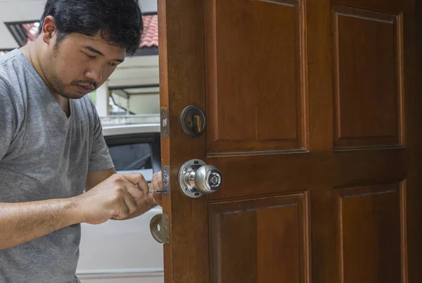 Locksmith fix the silver knob by screwdriver on wood door — Stock Photo, Image