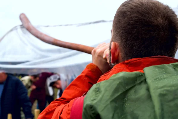 stock image Man in red jacket playing music at didgeridoo at holiday