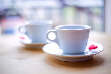 Ahşap masa üzerinde kırmızı kalpler tarafından dekore edilmiş çift bardak.