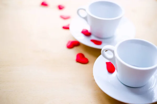 Δυο φλιτζάνια διακοσμημένο με κόκκινες καρδιές στο ξύλινο τραπέζι. — Φωτογραφία Αρχείου