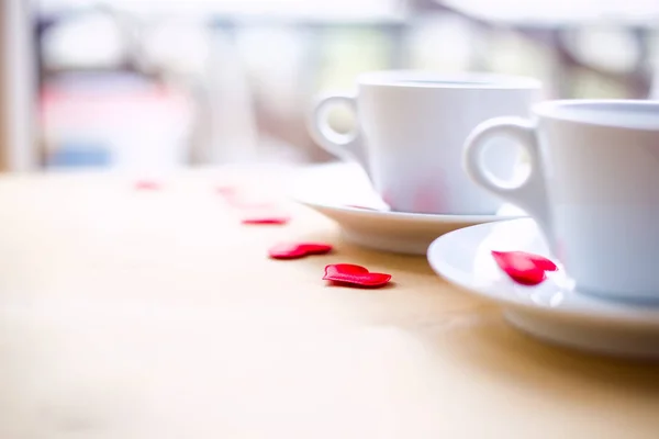 Δυο φλιτζάνια διακοσμημένο με κόκκινες καρδιές στο ξύλινο τραπέζι. — Φωτογραφία Αρχείου