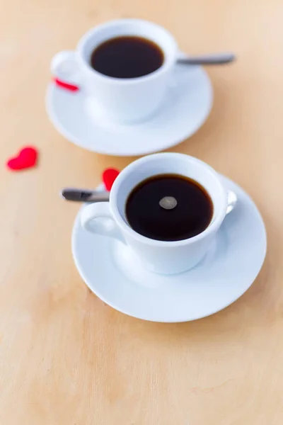 Δυο φλιτζάνια με καφέ, διακοσμημένο με καρδιές σε ξύλινο τραπέζι. — Φωτογραφία Αρχείου