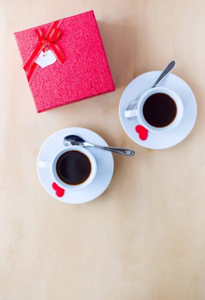 Δυο φλιτζάνια με καφέ, κιβώτιο δώρων και καρδιές σε ξύλινο τραπέζι. — Φωτογραφία Αρχείου