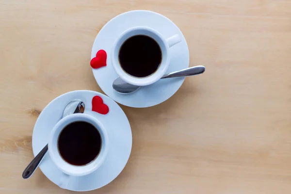 Δυο φλιτζάνια με καφέ, διακοσμημένο με καρδιές σε ξύλινο τραπέζι. — Φωτογραφία Αρχείου