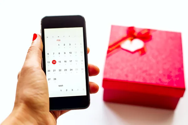 El ile beyaz artalanları, telefon ve kırmızı hediye kutusu
