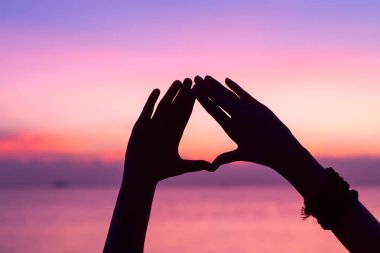 Gün batımı arka plan el ile kalp şekli