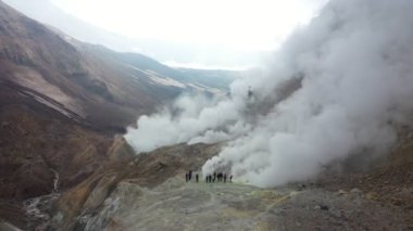 Volkan Krateri 'ndeki turistler. Volkanda yürüyüş. Kamçatka 'da krater sisi. Drone Video. Hava Görünümü.