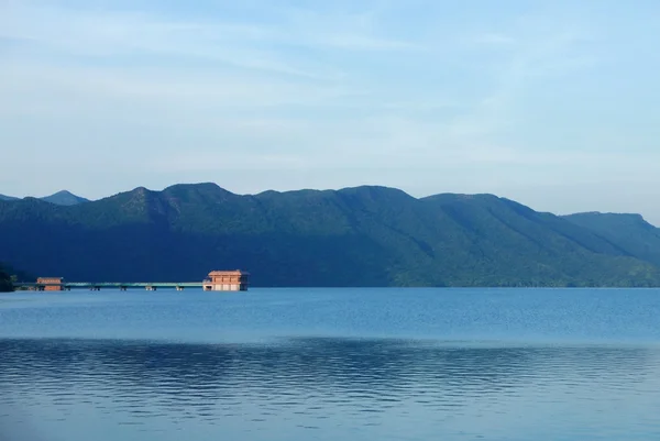 Building in reservoir, sky, and mountain — ストック写真