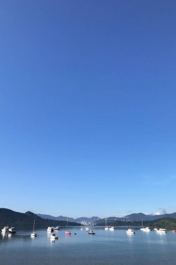 Dağ, mavi gökyüzü, tekne, yat ve yelkenli göl kenarında