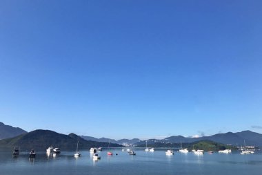 Dağ, mavi gökyüzü, tekne, yat ve yelkenli göl kenarında