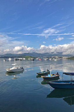 Dikey dağ, mavi gökyüzü, tekne, yat ve yelkenli göl kenarında