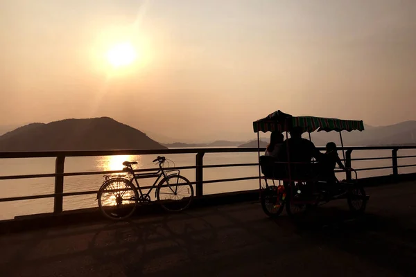 Silhouette of retro bicycle, family bike, fence, ocean, mountain