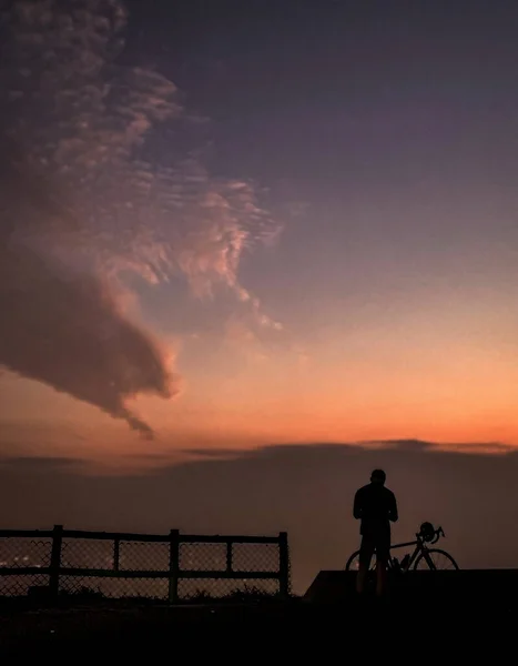 Silhouette of bicycle, rider and wooden fence at sunset — 스톡 사진