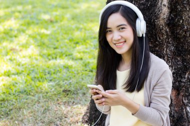 Güzel Asyalı kadın beyaz kulaklık ile müzik dinlemek