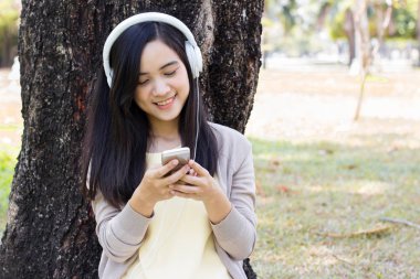 Güzel Asyalı kadın beyaz kulaklık ile müzik dinlemek