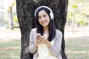 Güzel Asyalı kadın beyaz kulaklık ile müzik dinlemek