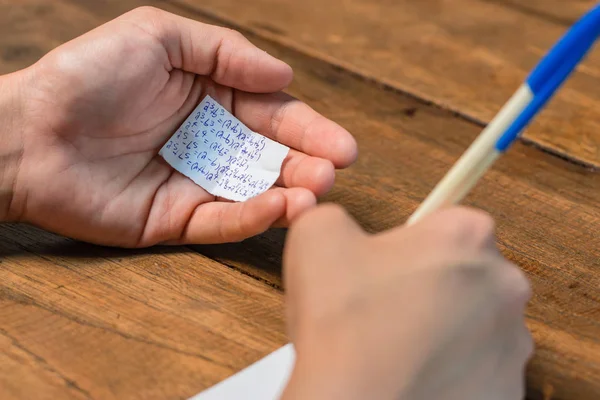 Gente haciendo trampa en la prueba por escrito respuesta en un pedazo de papel — Foto de Stock
