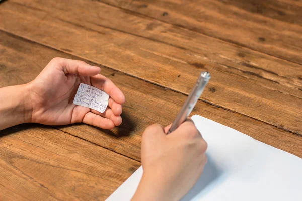 Gente haciendo trampa en la prueba por escrito respuesta en un pedazo de papel —  Fotos de Stock