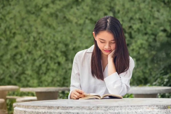 Mulher asiática lendo livro na mesa dentro do parque natural — Fotografia de Stock