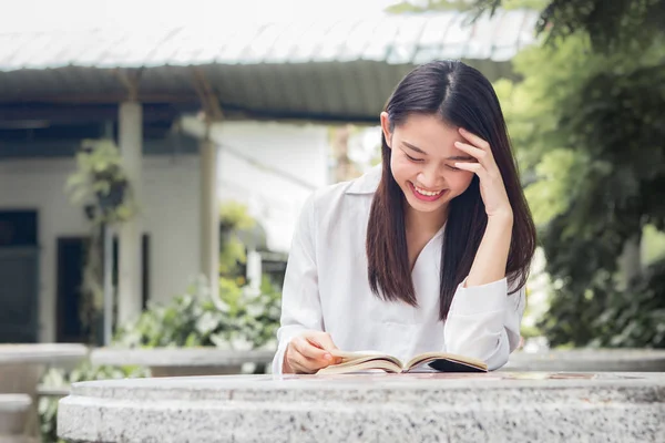 Asyalı kadın doğal park içindeki tablo üzerinde kitap okuma