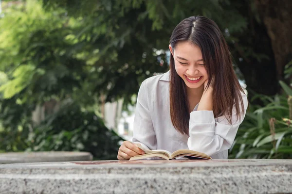 Asyalı kadın doğal park içindeki tablo üzerinde kitap okuma — Stok fotoğraf