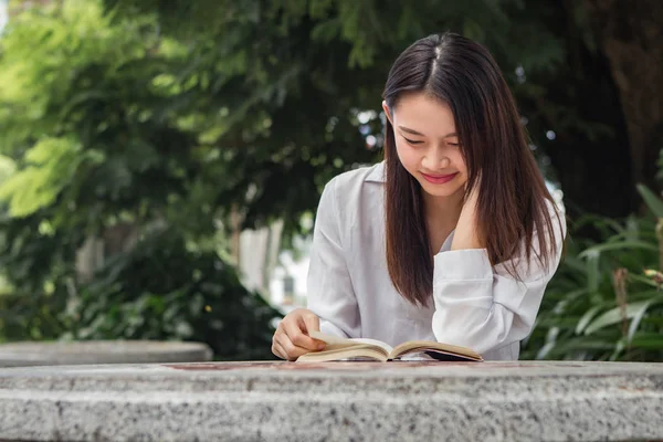 Asiatisk kvinna läser bok på bordet inuti naturparken — Stockfoto