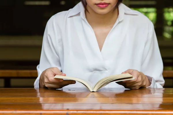 나무 탁자 위에서 책을 읽고 있는 여자 — 스톡 사진