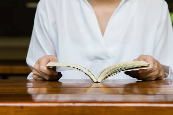 Frau liest Buch auf Holztisch — Stockfoto