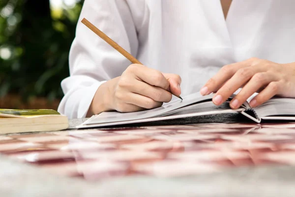 Mujer escribiendo en cuaderno con lápiz en la mesa en primer plano — Foto de Stock