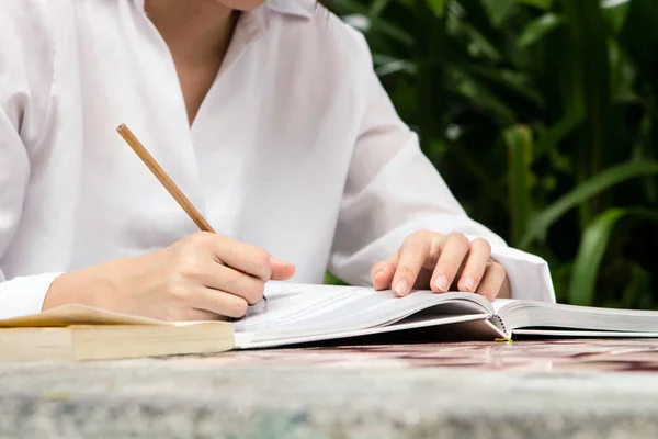 Frau schreibt auf Notizbuch mit Bleistift auf dem Tisch in Großaufnahme — Stockfoto