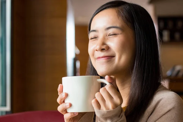 Asian woman drinking coffee from white coffee cup Stock Photo