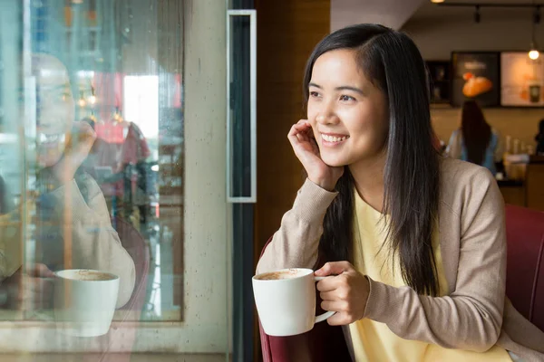 Asian looking outside window of coffee shop Royalty Free Stock Images