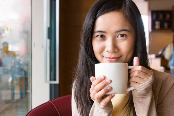 Asian woman drinking coffee in coffee shop